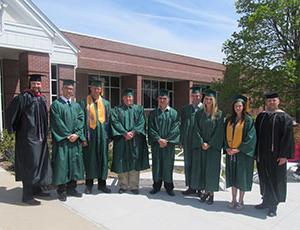 Veteran and military students and staff pose for a photo after graduation with their honor cords.